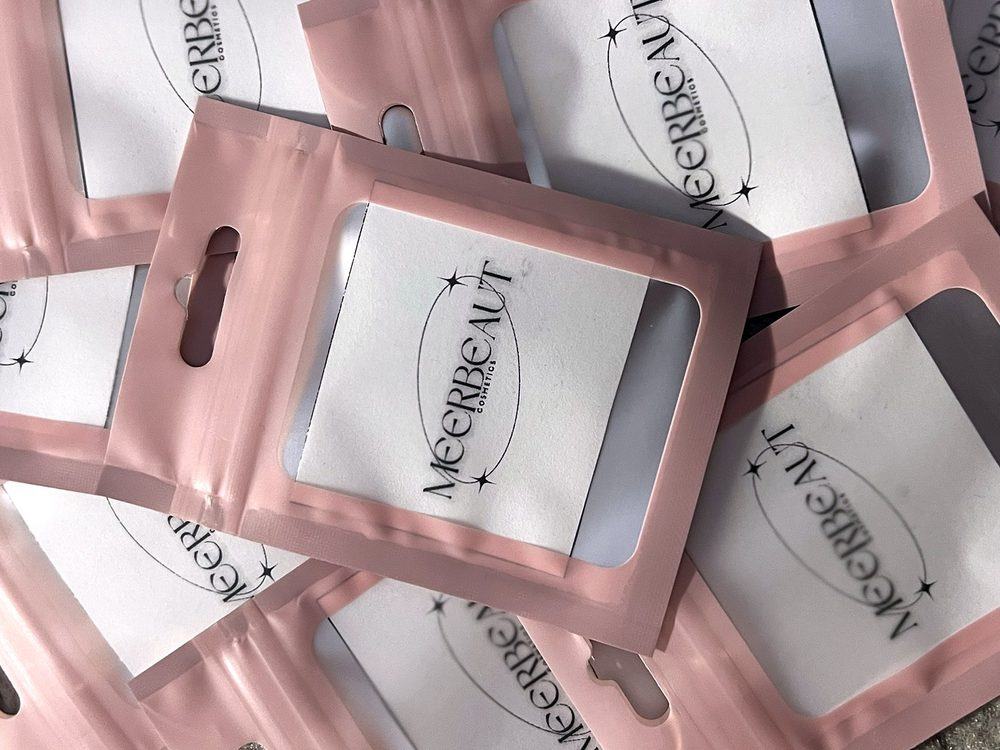 Pink pouches with white cards printed with the MEERBEAUT logo