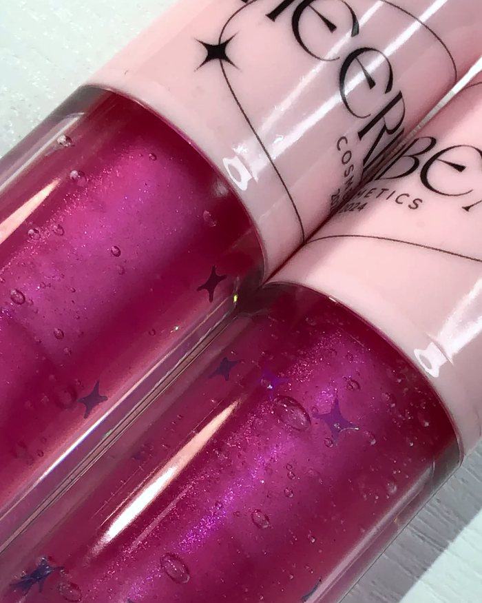 Close up of two berry glosses with star flecks and tiny bubbles
