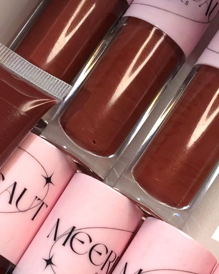 Close up of brown glosses laid in a box beside pink caps