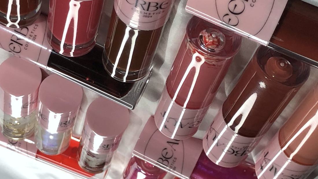 Rows of MEERBEAUT glosses in many shades and finishes laid out on white satin